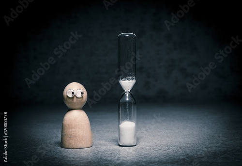 Deadline symbol with small figure watching hourglass countdown. Concept of time pressure, aging alone and business pressure. photo