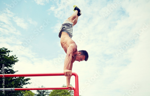 Obraz na plátně young man exercising on parallel bars outdoors
