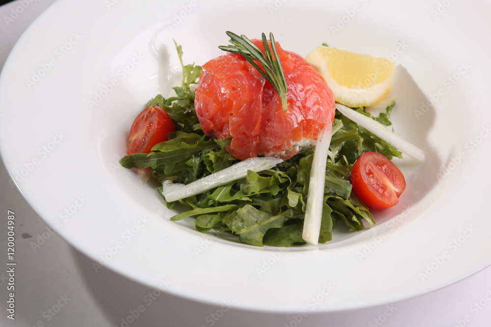 Red fish on Arugula in white plate Red fish on Arugula in white plate