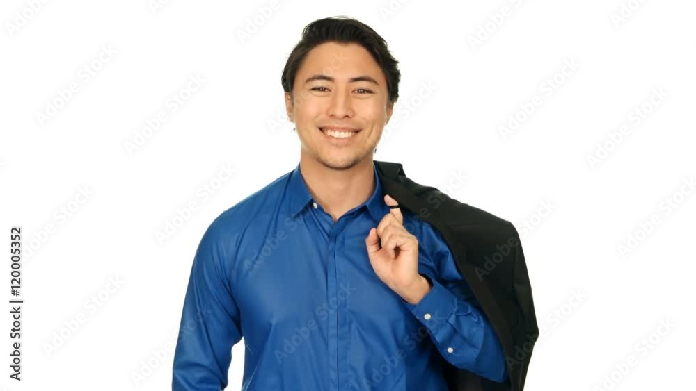 An attractive man wearing a blue shirt with a blazer over his shoulder, walking in front of a white background smiling towards camera. Shot in 4K. An attractive man wearing a blue shirt with a blazer over his shoulder, walking in front of a white background smiling towards camera. Shot in 4K.