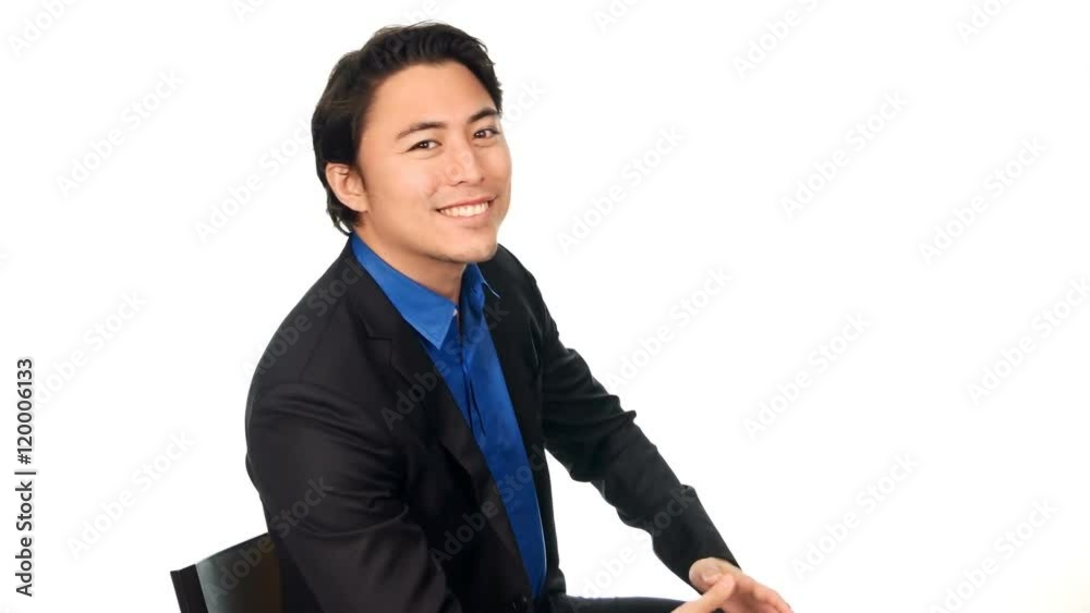 Attractive businessman in a blue shirt and black suit, walking and sitting down on a chair in front of a white background. Shot in 4K. Attractive businessman in a blue shirt and black suit, walking and sitting down on a chair in front of a white background. Shot in 4K.
