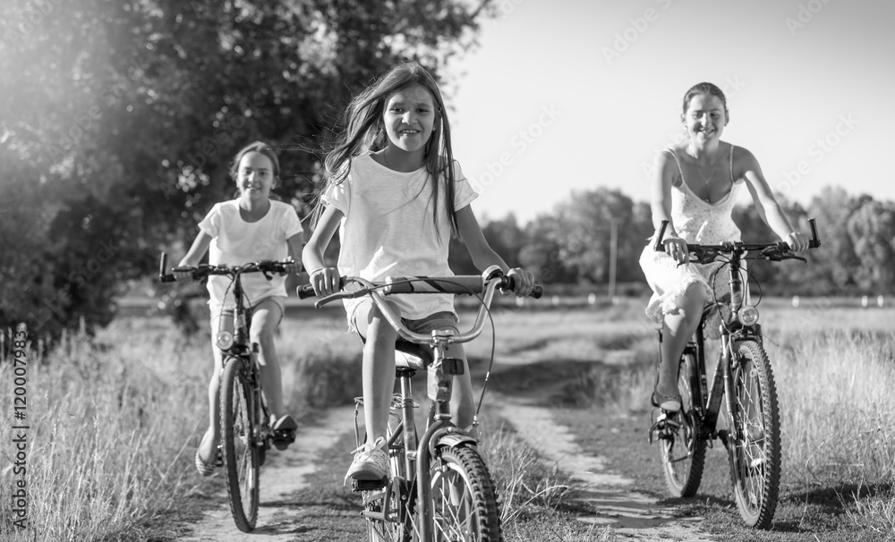 Obraz premium Black and white image of young mother riding on bicycles with tw