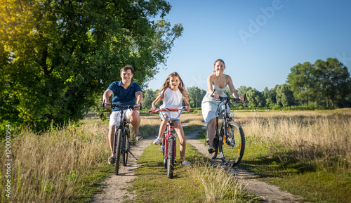 Young family riding on bicycles at meadow. Concept of family spo