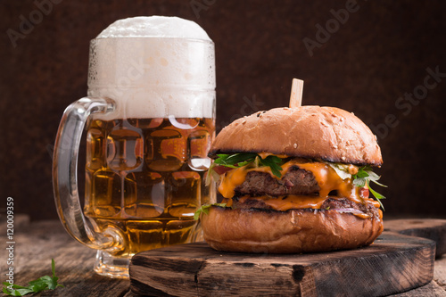 Fresh and tasty hamburger with a beer on a wooden table.