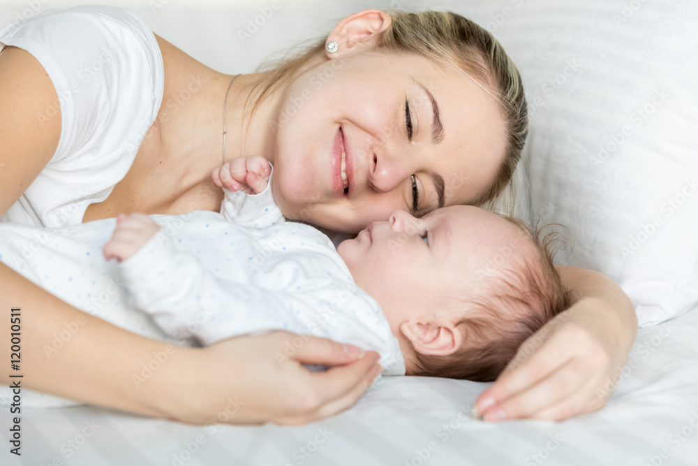 Portrait of beautiful smiling woman lying with her cute baby on Portrait of beautiful smiling woman lying with her cute baby on