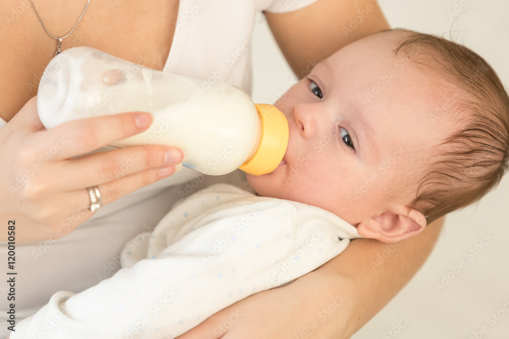 Toned portrait of young mother holding her baby boy and feeding Toned portrait of young mother holding her baby boy and feeding