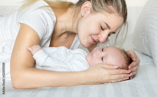 Portrait of beautiful young mother cuddling her baby boy on bed