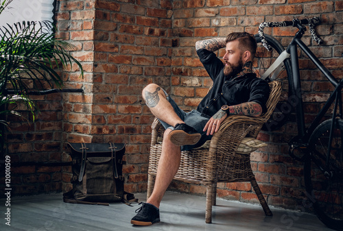The bearded hipster male relaxing in a chair. photo