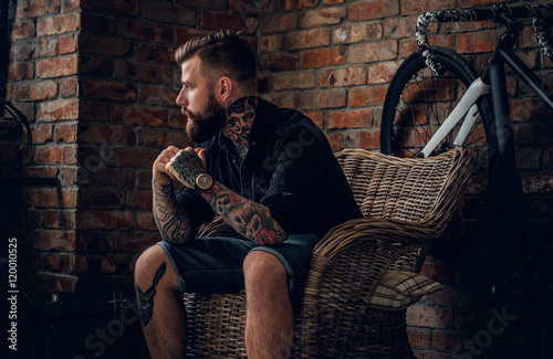 The bearded hipster male relaxing in a chair.