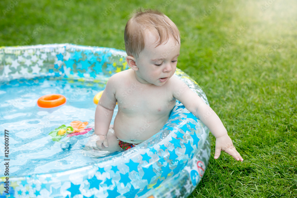 Happy baby in the inflatable swimming pool at backyard