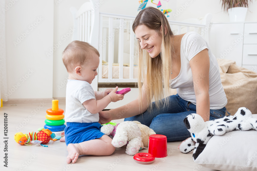 Adorable baby playing with toy cellphone on floor at living room