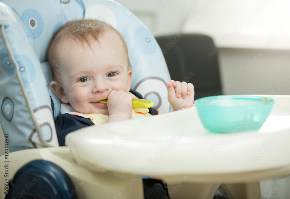 Portrait of adorable smiling baby eating porridge itself with sp Portrait of adorable smiling baby eating porridge itself with sp
