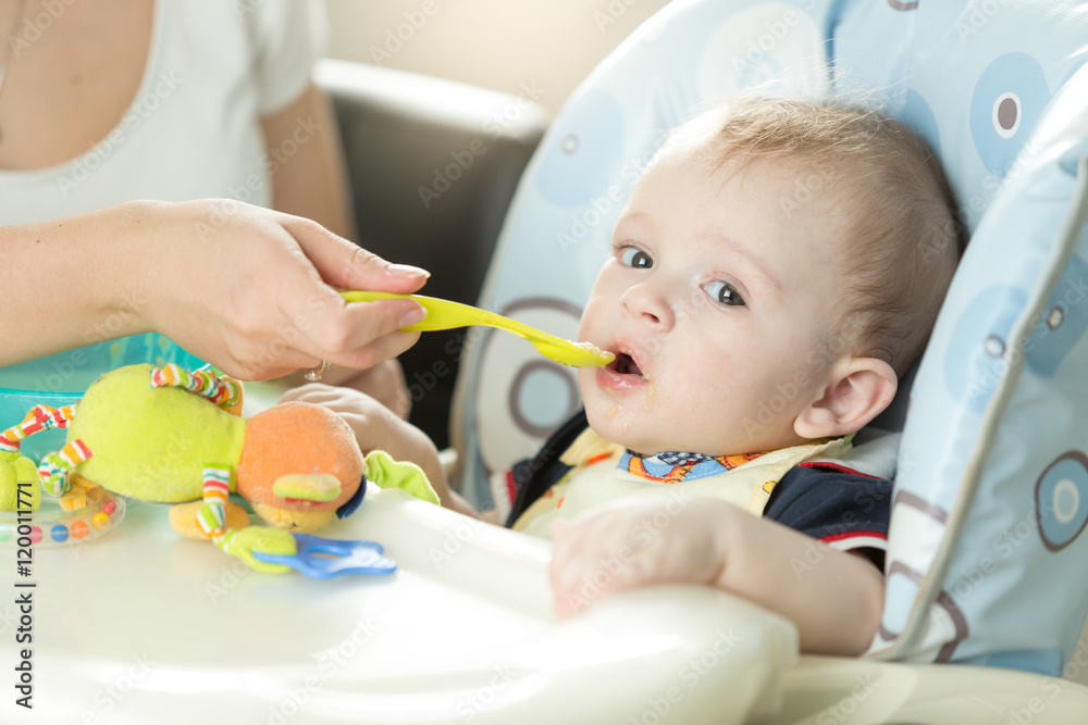 Portrait of cute adorably baby boy sitting in chair and eating f Portrait of cute adorably baby boy sitting in chair and eating f