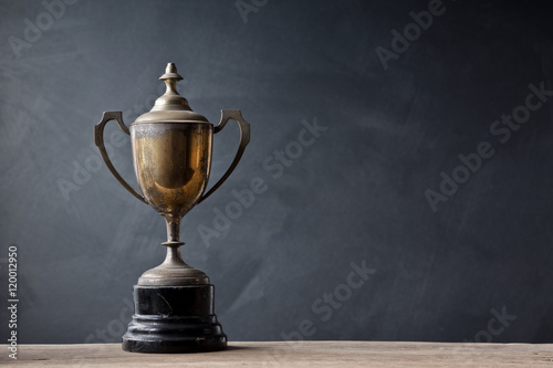 still life photography : old trophy on old wood with space of art dark background