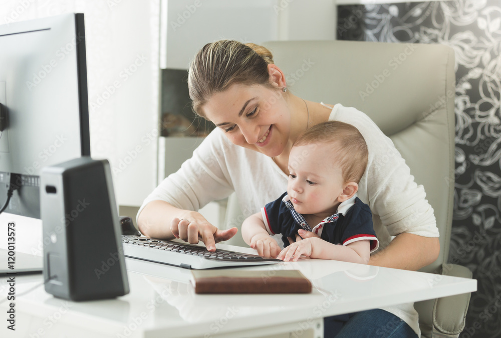 Elegant woman teaching her baby how to use computer Elegant woman teaching her baby how to use computer