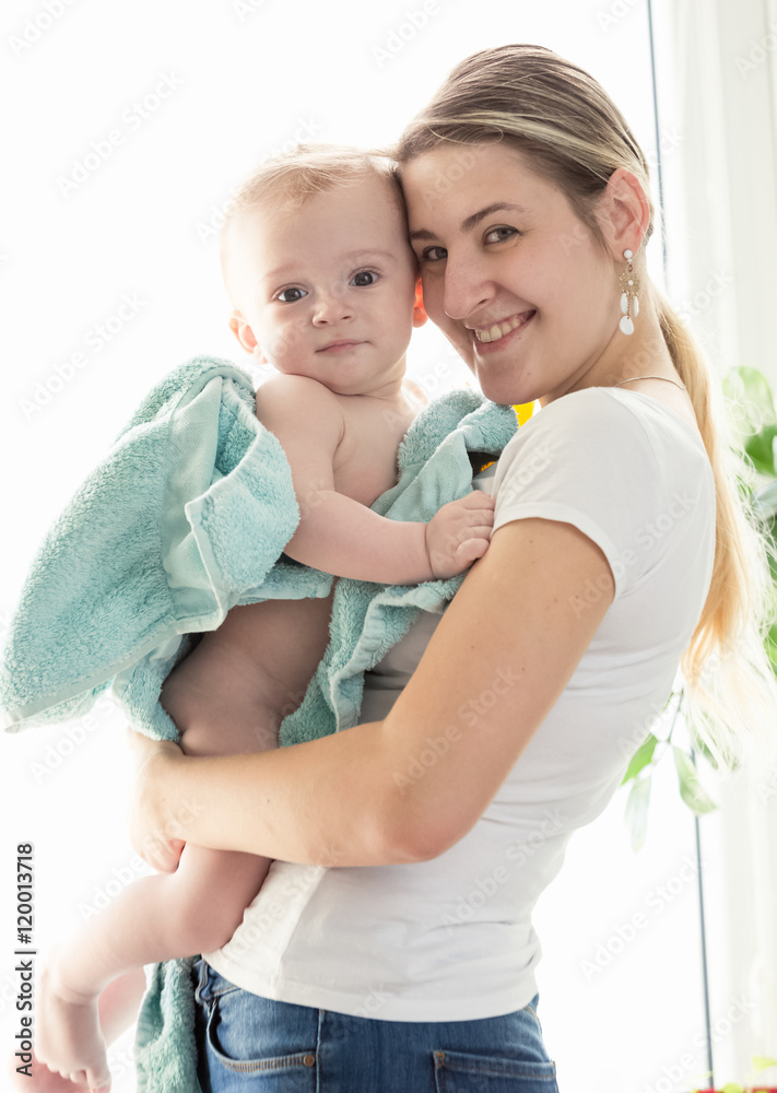 Toned portrait of happy mother hugging her baby boy covered in b Toned portrait of happy mother hugging her baby boy covered in b