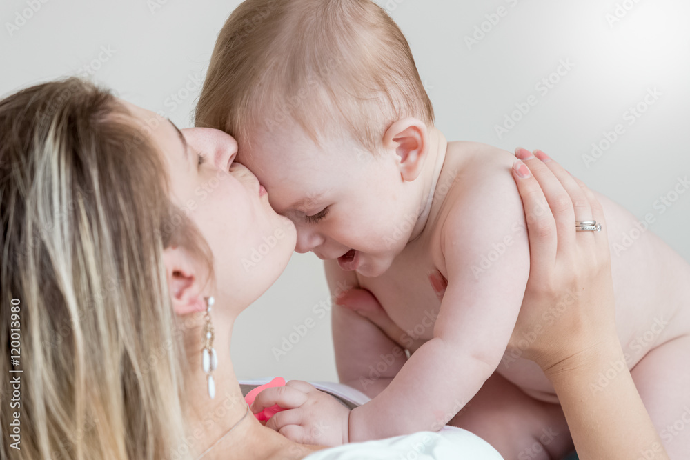 Happy mother kissing 9 months old baby in head Happy mother kissing 9 months old baby in head