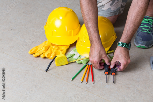 Human hands organizing work tools: safety hardhats gloves, pencils, screwdrivers