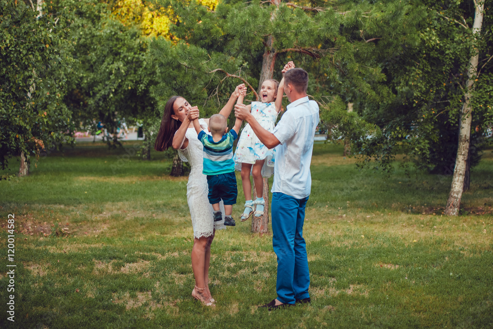 Fototapeta premium Young family of four having fun in the park