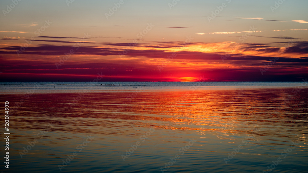 Beautiful summer sunset at the river with blue sky, red and oran