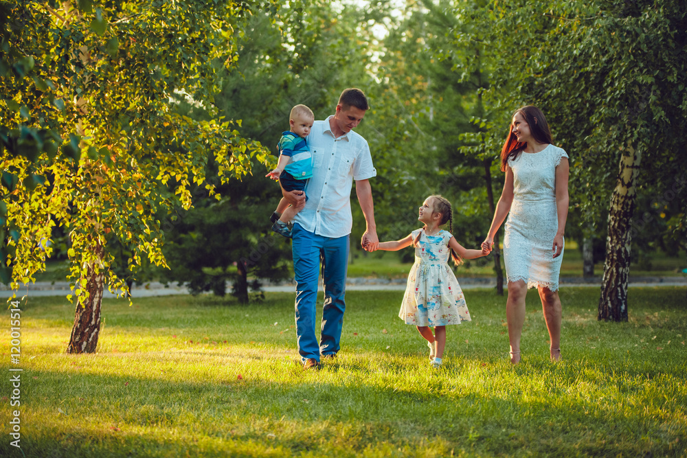 Fototapeta premium Happy young family of four people walking and having fun in the park