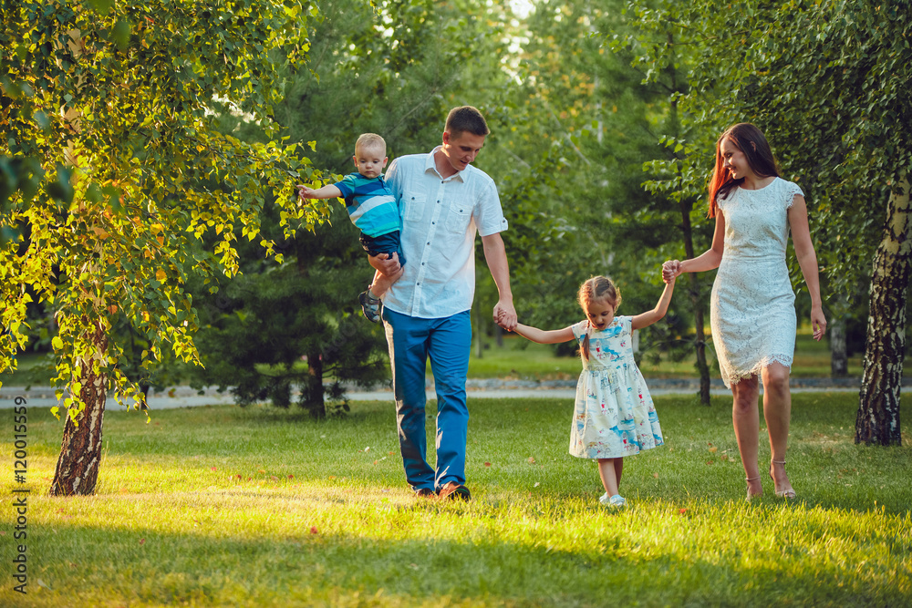 Happy young family of four people walking and having fun in the park Happy young family of four people walking and having fun in the park