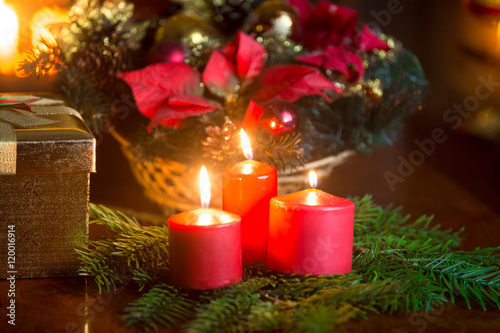 Decorative wreath with burning red candles on table at living ro