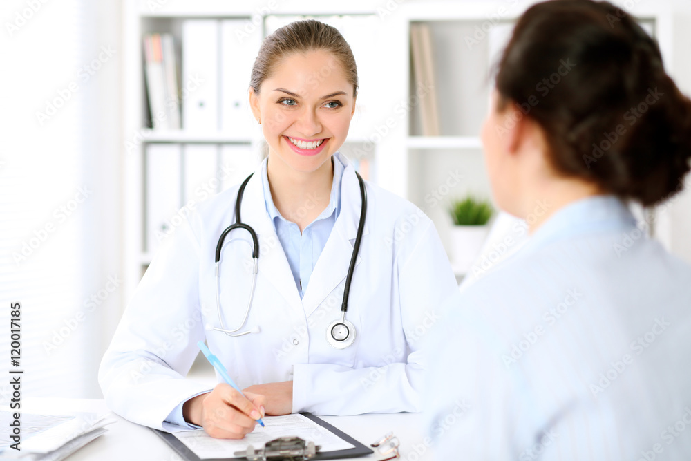 Friendly smiling doctor and patient sitting at the table. Very good news and high level medical service concept. Friendly smiling doctor and patient sitting at the table. Very good news and high level medical service concept.