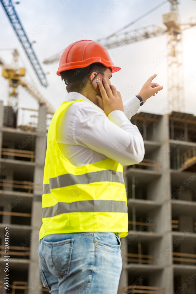 Construction engineer pointing with finger at building under con Construction engineer pointing with finger at building under con