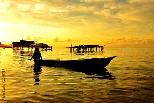 Silhouette of a Bajau Laut kid on a traditional boat during sunrise in Maiga island in Sabah Borneo  Malaysia.