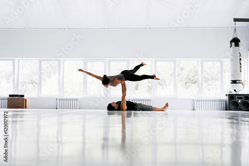 Couple practicing acro yoga in white studio. Acro yoga concept. Pair yoga. Yoga flexibility class workout