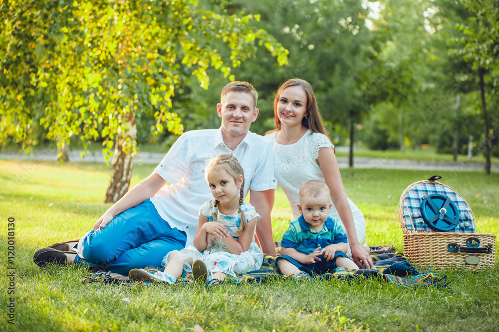 Young happy family of four on picnic in the park