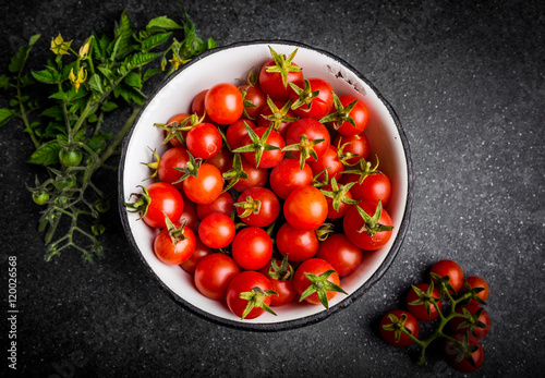 Small cherry tomato in bowl on black background