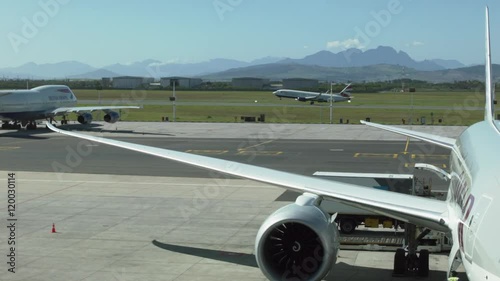 planes are in the airport of Cape Town against mountains. On a background on a runway the plane takes off.