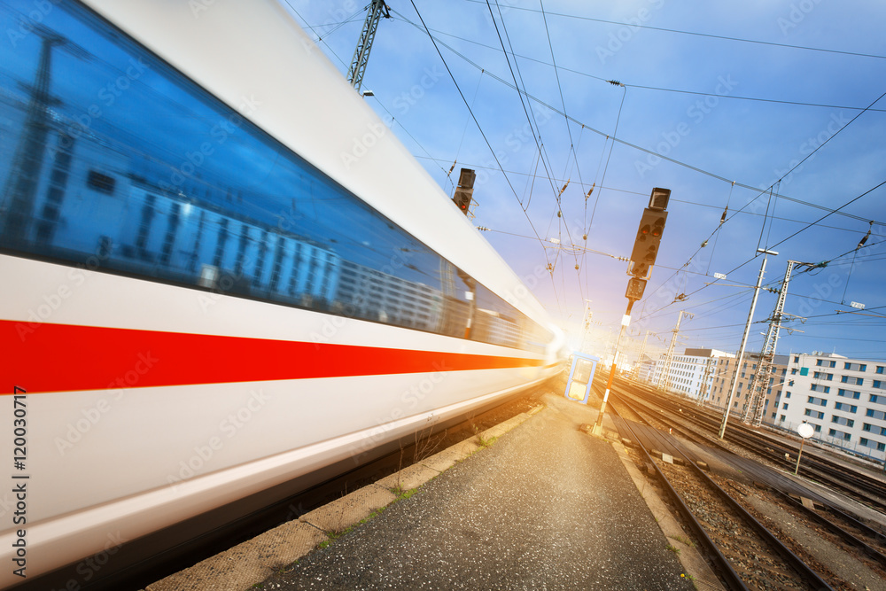 High speed white passenger train on tracks in motion at sunset. Commuter train. Railway station. Railroad with vintage toning. Travel background. Train High speed white passenger train on tracks in motion at sunset. Commuter train. Railway station. Railroad with vintage toning. Travel background. Train