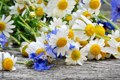 A bouquet of daisies and cornflowers on wooden table. Postcard of wild flowers.