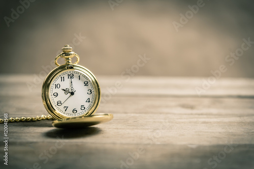 Old vintage gold pocket watch on wooden floor.