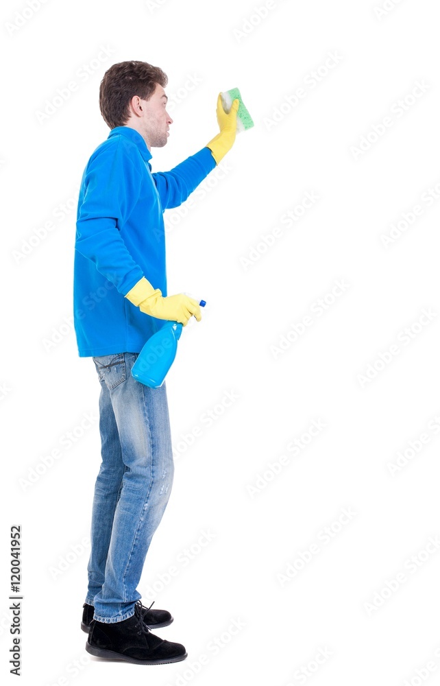 side view of a cleaner man in gloves with sponge and detergent. Curly boy in a blue sweater in the process of cleaning .. side view of a cleaner man in gloves with sponge and detergent. Curly boy in a blue sweater in the process of cleaning ..