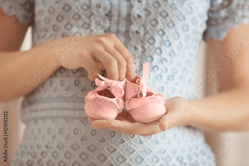 Pregnant woman holding pink baby booties