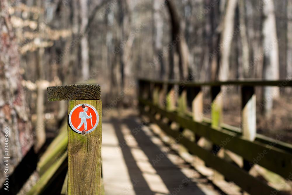 Bridge over a creek with a red hiking trail marker.