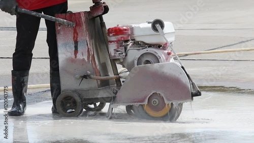 A worker cutting concrete road with diamond saw blade machine
