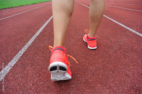 runner legs on red running track in stadium