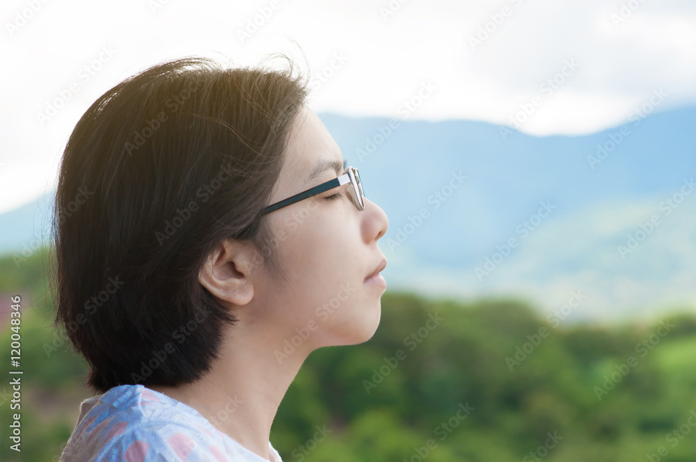 Asian woman standing at balcony and breathing fresh air.