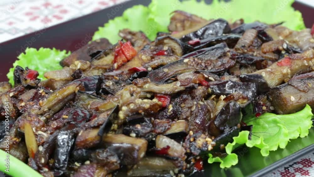 Baked eggplant with onions, garlic, red hot chili pepper and walnuts on the black plate, close up Baked eggplant with onions, garlic, red hot chili pepper and walnuts on the black plate, close up