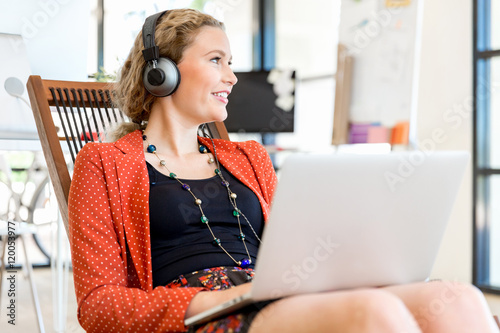 Young woman listening to the music while working on a computer