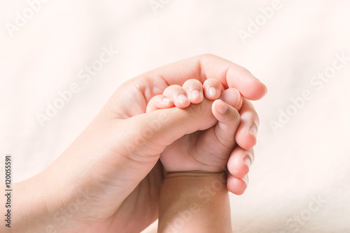 Baby hand holding finger mom on vintage tone. (Selected focus)