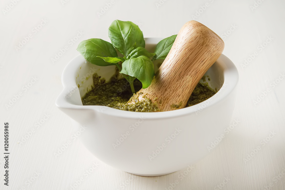 Homemade green pesto sauce with basil and pine nuts in white mor
