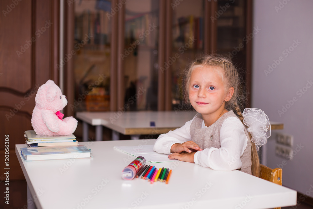 Little girl in the class has been learned. During the break sitting on the table next to her favorite toy bear Little girl in the class has been learned. During the break sitting on the table next to her favorite toy bear