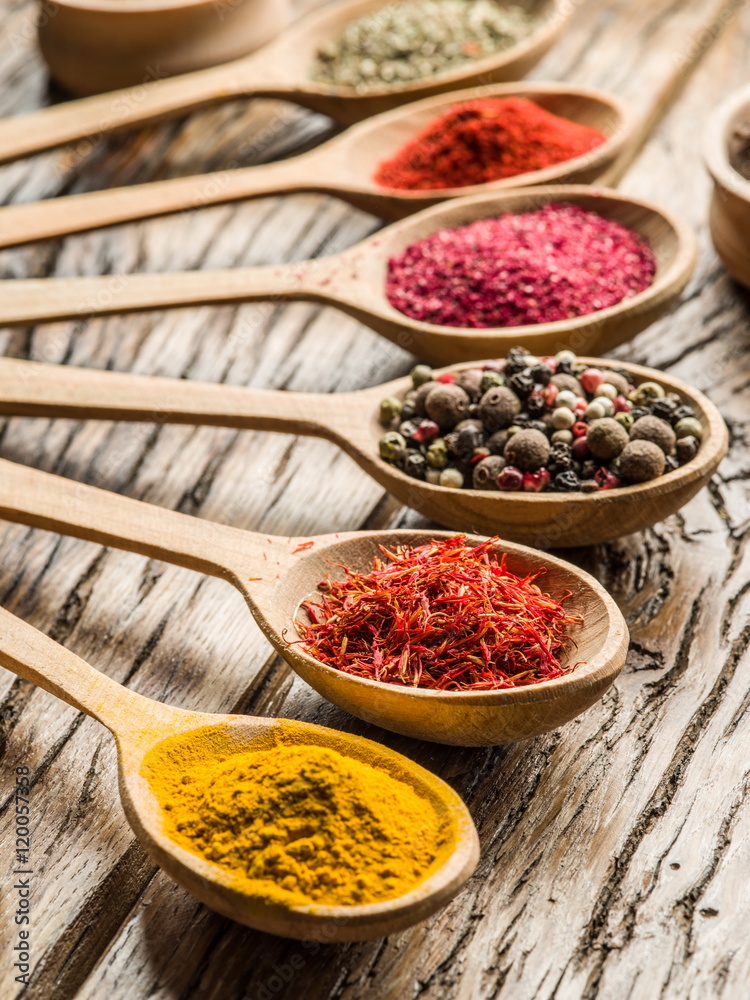 Assortment of colorful spices in the wooden spoons.