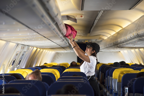 Traveller woman open overhead locker on airplane 